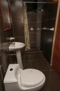 y baño con aseo, lavabo y ducha. en Hotel Residencial San Isidro, en Hualmay