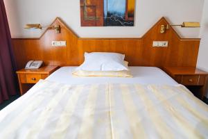 ein Bett in einem Zimmer mit zwei Nachttischen und einem Telefon in der Unterkunft Hotel-Restaurant Moris in Walferdange