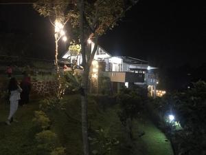 une maison éclairée la nuit avec un arbre dans l'établissement Villa Kay Mountain, à Bogor