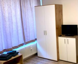 フェルトキルヒにあるHotel am Bahnhofの白いキャビネットとテレビ付きのベッドルーム1室