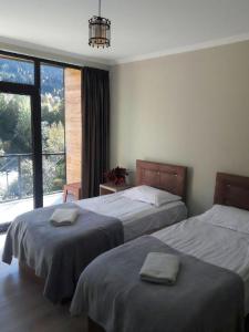 a bedroom with two beds and a large window at Guest House Mari30 in Mestia