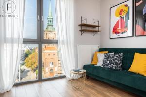 a living room with a green couch and a large window at Flatbook - City Center Apartments in Gdańsk