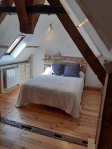 een slaapkamer met een groot bed op zolder bij Le gîte des pierres in Nogent-le-Rotrou