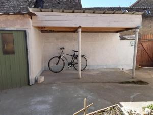 een fiets geparkeerd onder een luifel in een garage bij Le gîte des pierres in Nogent-le-Rotrou