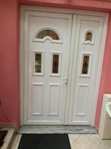 białe drzwi z dwoma oknami na różowej ścianie w obiekcie Villa Center w Tiranie