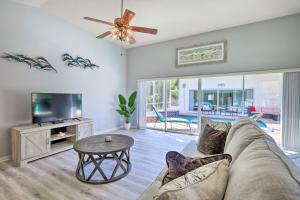 ein Wohnzimmer mit einem Sofa, einem TV und einem Tisch in der Unterkunft Merritt Island Home with Grill and Saltwater Pool in Merritt Island