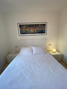 a bedroom with a white bed with a picture on the wall at Garibaldi18 in Desenzano del Garda