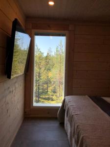 Dormitorio con ventana grande en una cabaña en Rokovan Helmi - Natural peace in Ruka-Kuusamo, en Ruka