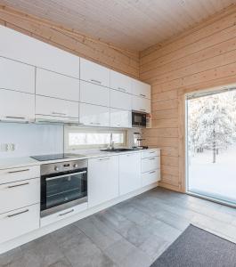 a kitchen with white cabinets and a large window at Rokovan Helmi - Natural peace in Ruka-Kuusamo in Ruka