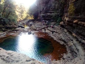 um grupo de pessoas andando em torno de uma piscina de água em um canyon em Shalom guest house em Cherrapunji