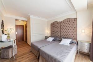 a bedroom with a large bed with a large headboard at Essence Hotel Boutique in Torremolinos