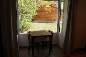 埃尔卡拉法特Departamentos-Cabañas y Habitaciones Compartidas El Puente的有窗户的房间里有一张桌子和两把椅子