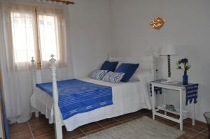 a bedroom with a bed with blue sheets and a window at Casa Amanada in Santa Margalida