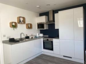 een keuken met witte kasten en een wastafel bij Beautifully Furnished 1 Bed Town Centre Apartment in Bournemouth
