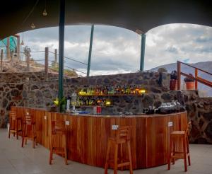 a bar with chairs around it with a stone wall at Vertical Sky Suites in Ollantaytambo