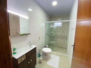 a bathroom with a shower and a toilet and a sink at Calefe Suítes in Penha