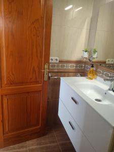 a bathroom with a white sink and a wooden door at adosado cerca del mar in Playa Honda +9 photos