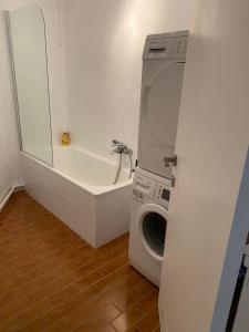 een badkamer met een wasmachine en een bad bij Lichtrijk mooi appartement met zicht op hof van Roosendael in Antwerpen