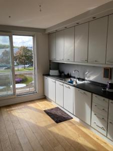a kitchen with white cabinets and a large window at Lichtrijk mooi appartement met zicht op hof van Roosendael in Antwerp