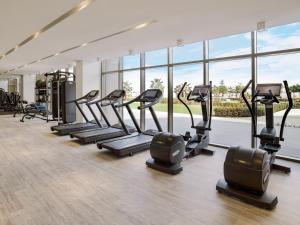 un gimnasio con una fila de cintas de correr y elípticas en LUXURY APARTMENT / 2 BR / BRAND NEW / PRIVATE BEACH / THE8 en Dubái