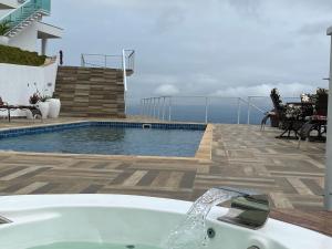 a bath tub sitting on a patio next to a swimming pool at Alta Vista Pousada Boutique in Córrego do Bom Jesus