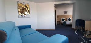 a living room with a blue couch in a hotel room at Hotel du Golf Coignieres in Coignières