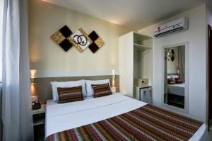 a bedroom with a large white bed and a mirror at Transamerica Fit Vitória Praia de Camburi in Vitória +57 photos