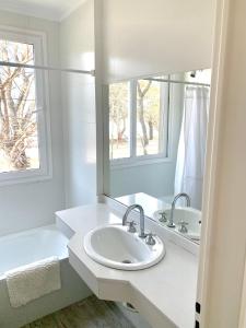 ein weißes Badezimmer mit einem Waschbecken und einem Spiegel in der Unterkunft Espectacular departamento sobre la laguna para parejas in Chascomús