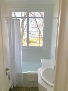 baño blanco con lavabo y ventana en Espectacular departamento sobre la laguna para parejas en Chascomús