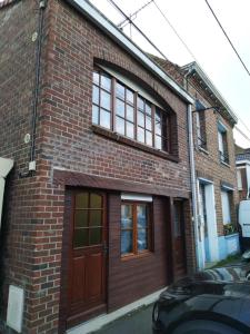 een bakstenen gebouw met een bruine deur en ramen bij Maison des Flandres in Oxelaere