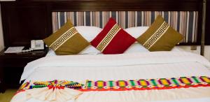 Una cama blanca con almohadas coloridas encima. en Sonia Hotel, en Accra
