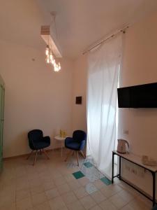 sala de estar con 2 sillas y cortina blanca en Le Nuvole di Ortigia en Siracusa
