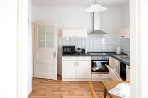 a kitchen with white cabinets and a stove top oven at Ferienwohnungen Kleinräschen in Großräschen