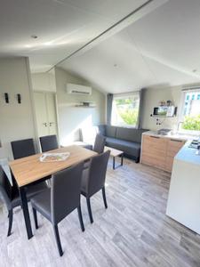 a room with a table and chairs and a kitchen at Mobilhome Salsa XXL in Gastes