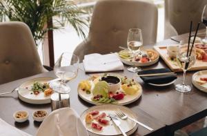 a table with plates of food and glasses of wine at Lux Pegaz 008 in Vrnjačka Banja