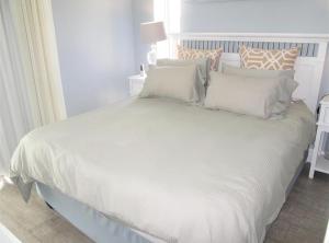 una cama blanca con sábanas y almohadas blancas en Seabreeze At 301, en Ballito