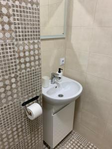La salle de bains est pourvue d'un lavabo et d'un rouleau de papier toilette. dans l'établissement 0263-1 Смарт-апартаменты ЖК «Счастливый», à Kiev
