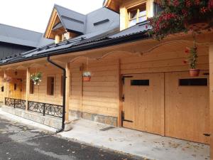 a wooden building with a garage with two doors at Wypoczynek u Hazów in Chochołów