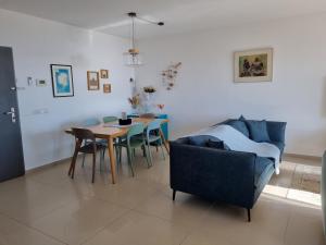 ein Wohnzimmer mit Sofa, Tisch und Stühlen in der Unterkunft 7th Floor in Akkon