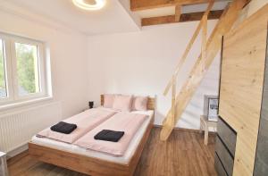 sypialnia z łóżkiem z różową pościelą i drewnianą podłogą w obiekcie Apartmany Troll w mieście Bublava