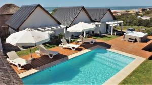 a house with a swimming pool with chairs and umbrellas at Kanaloah Lodge & Cabins in Punta Del Diablo