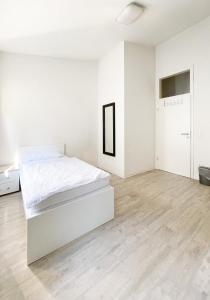 a white bedroom with a bed and a wooden floor at Traumhaftes Privatzimmer in Karlsruhe in Karlsruhe