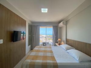a hotel room with a large bed and a window at AllMar Flats - Apartamentos frente mar - Beach Village in Fortaleza