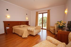Hotel Panoramic Montepulciano في مونتيبولسيانو: غرفة نوم بسرير واريكة ونافذة