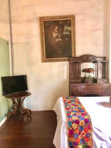 a bedroom with a bed and a tv and a painting at Hotel Boutique Los Camilos in Mexico City