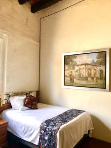 a bedroom with a bed with a painting on the wall at Hotel Boutique Los Camilos in Mexico City