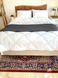 a bed with a white comforter and a rug at Rooftop View in Utrecht