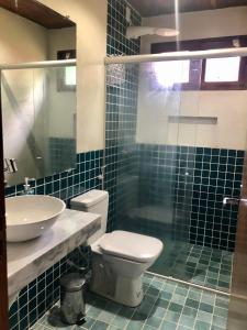 a blue tiled bathroom with a toilet and a sink at Casa Bromélia Green in Itacaré