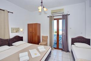 a bedroom with two beds and a balcony at Aspous Studios and Rooms in Skiros