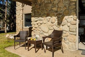 three chairs and a table in front of a stone wall at Standard Two Bedroom - Aspen Alps 101 in Aspen